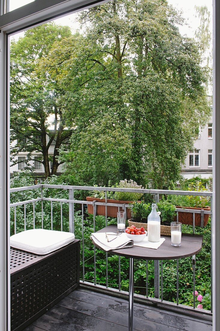 Milk, strawberries, eyeglasses and newspaper on balcony table