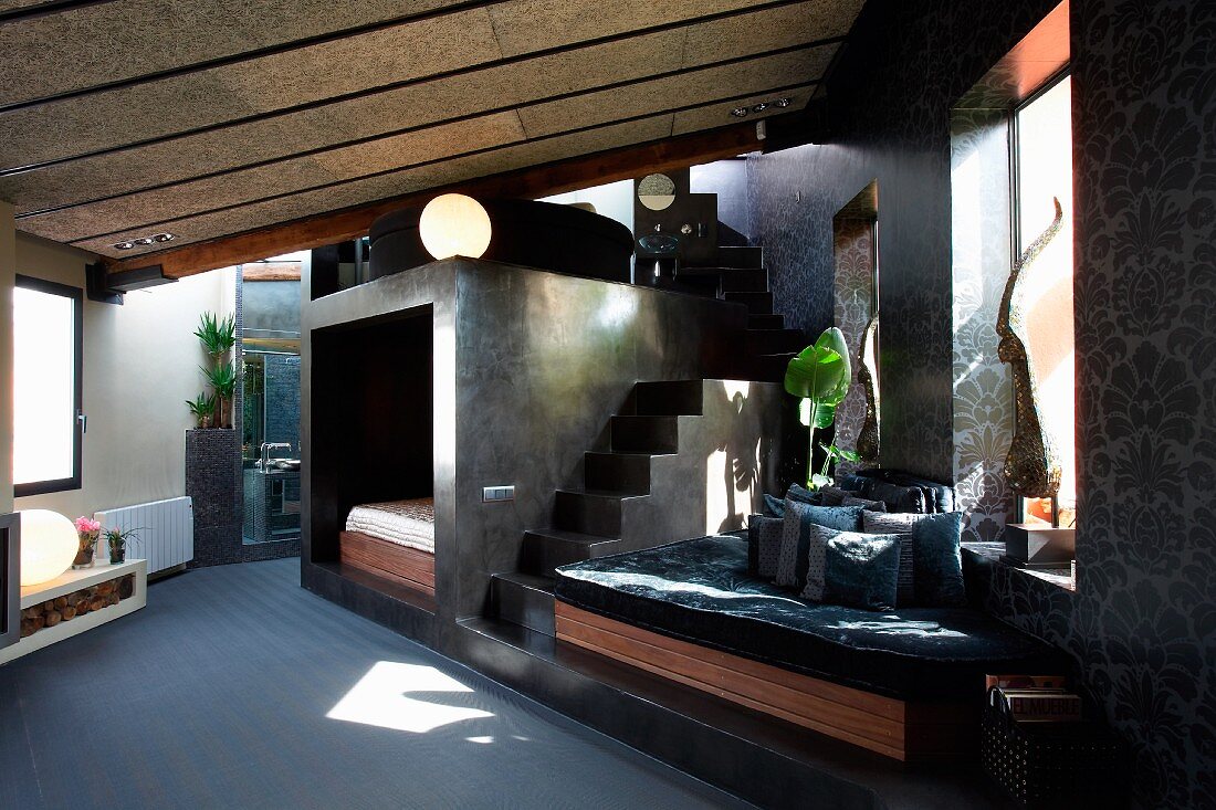 Open-plan interior with seating area below window and staircase next to bedroom installation