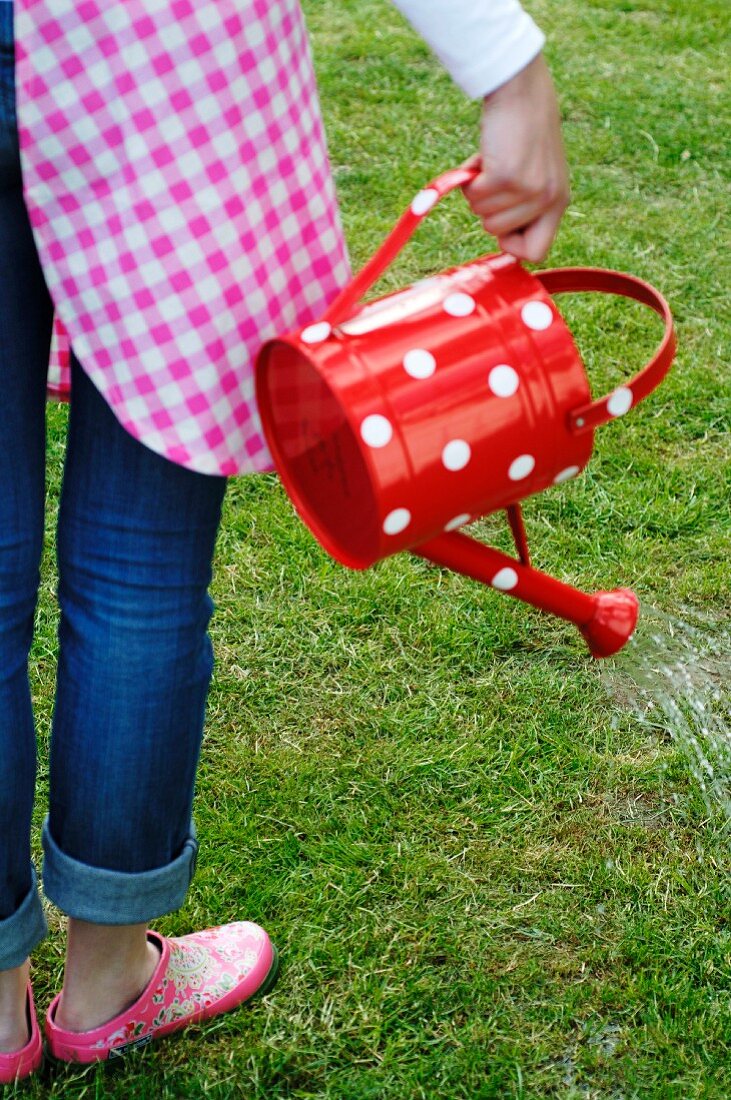 Frau im Garten bewässert Rasen