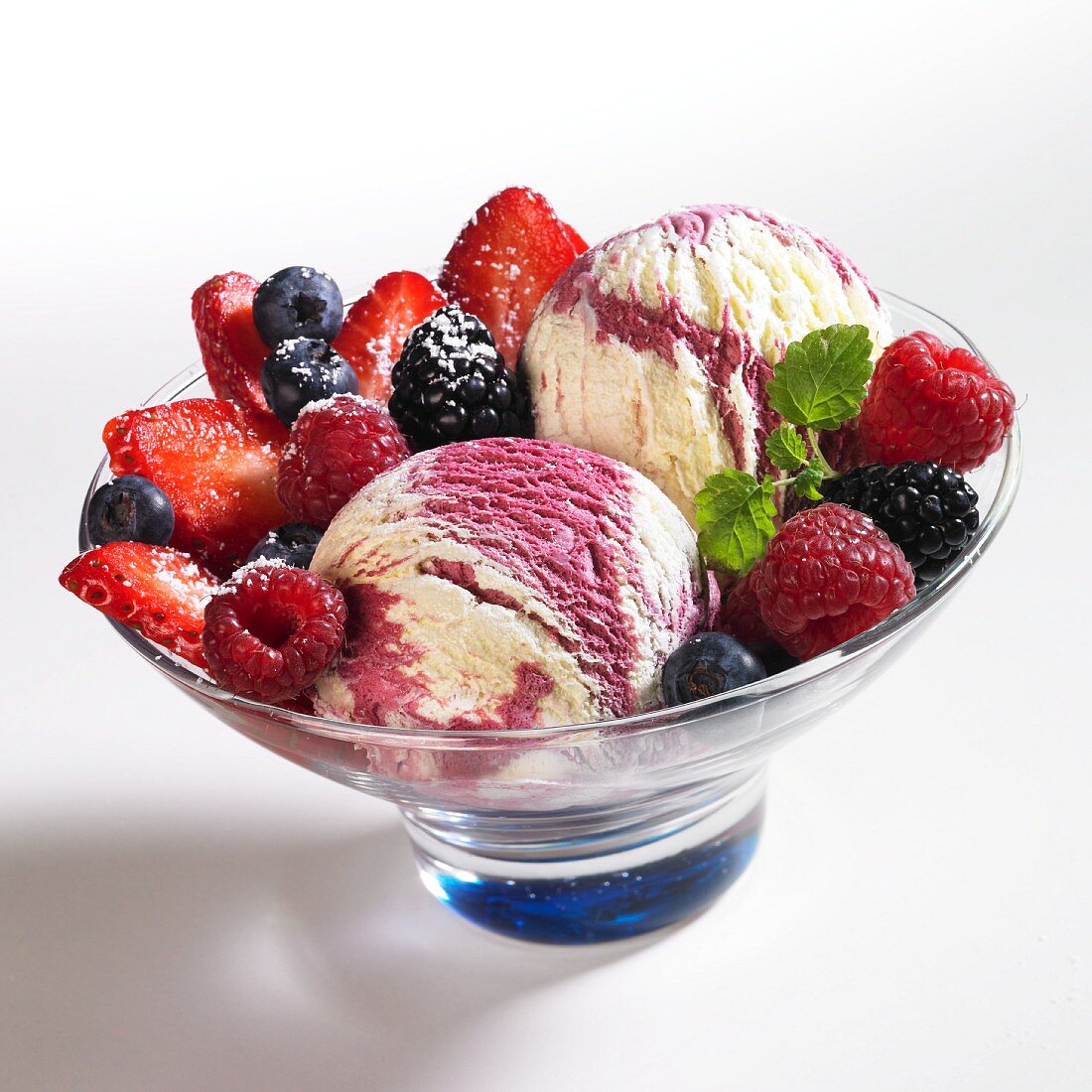 Vanilla and berry ice cream with raspberries, blueberries, blackberries, icing sugar, cream and lemon balm