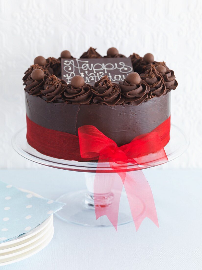 A chocolate cake with a ribbon and the word Happy Birthday