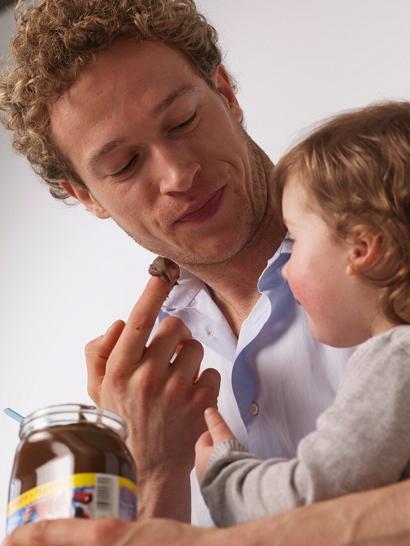 Vater und Tochter naschen Nussnougatcreme