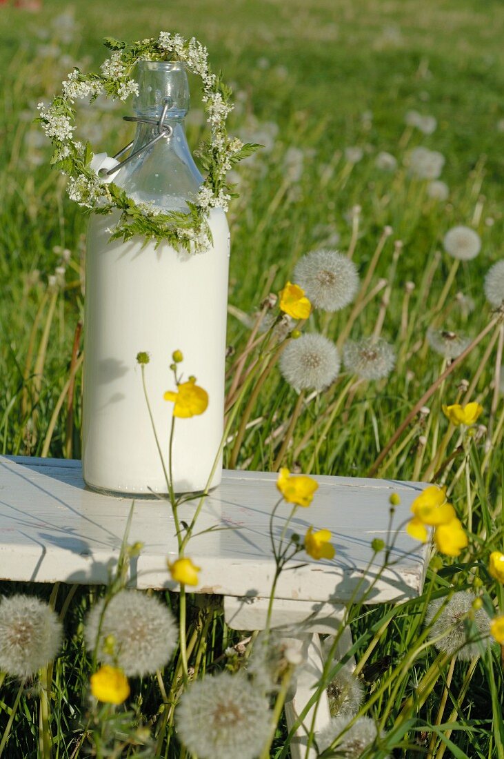 Milchflasche und Blumenschmuck