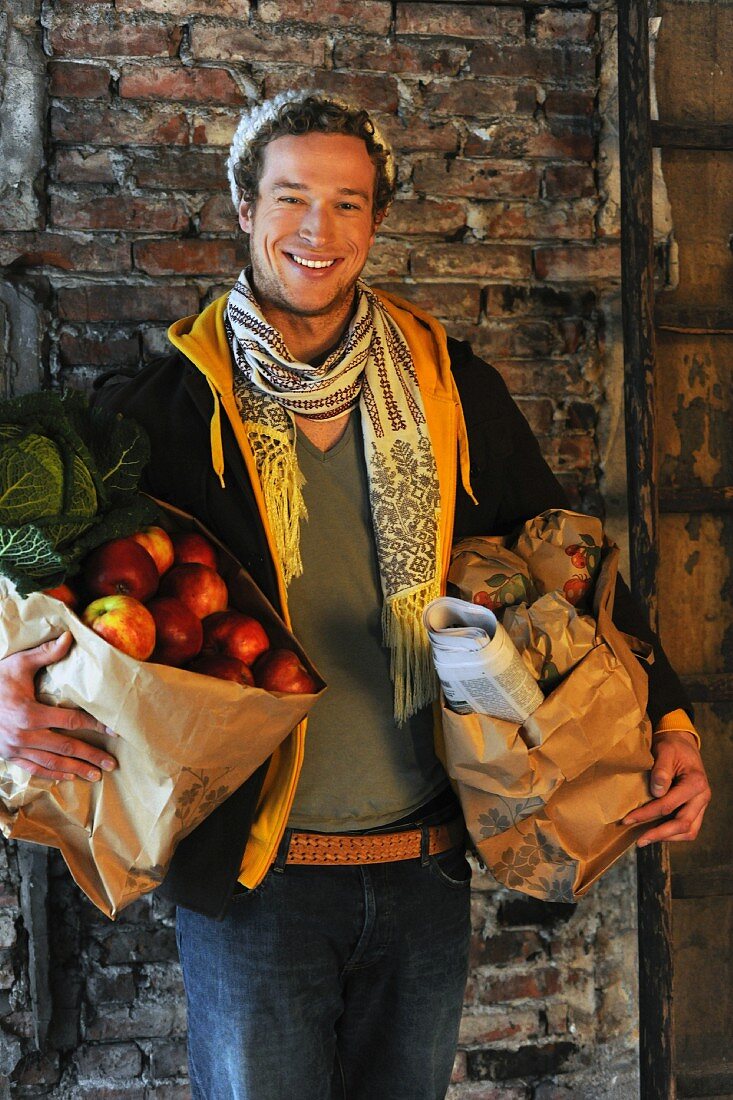 Mann trägt Einkaufstaschen mit Obst und Gemüse