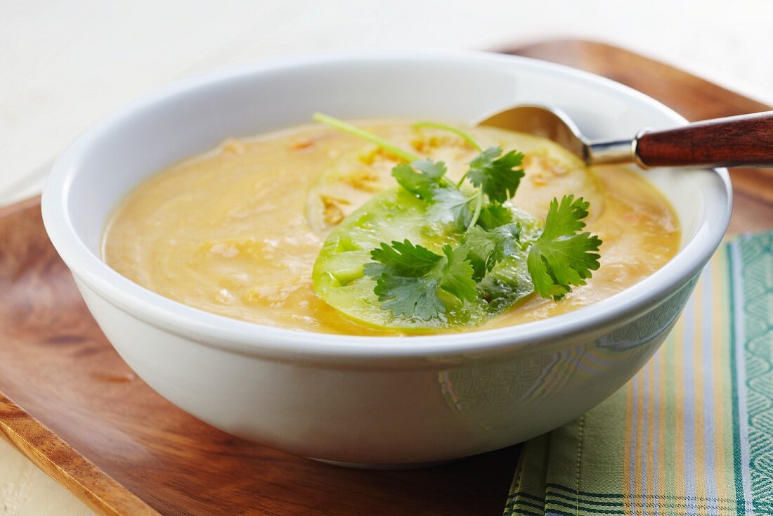 A Bowl of Creamy Squash and Corn Soup with Tomatillo and Cilantro Garnish