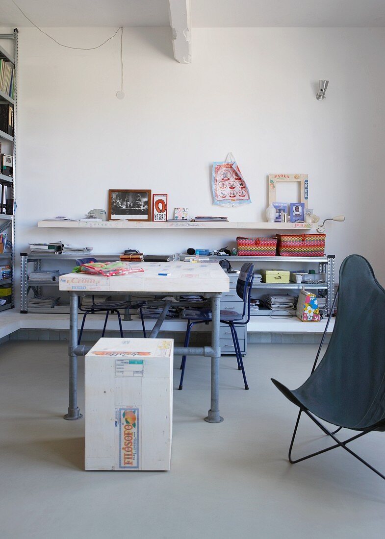 Selbstgebauter Tisch aus Gerüststangen vor halbhohem Regal in minimalistischem Wohnraum