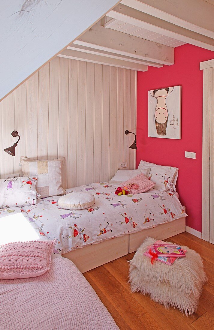 Bright child's bedroom - flokati pouffe in front of bed against white wooden wall and pink-painted wall