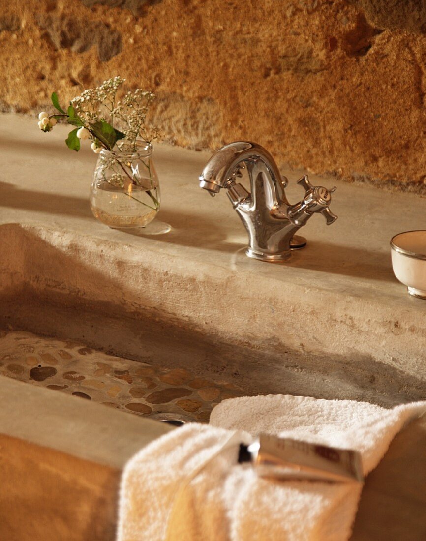 Concrete wash basin with vintage tap fittings against rustic wall