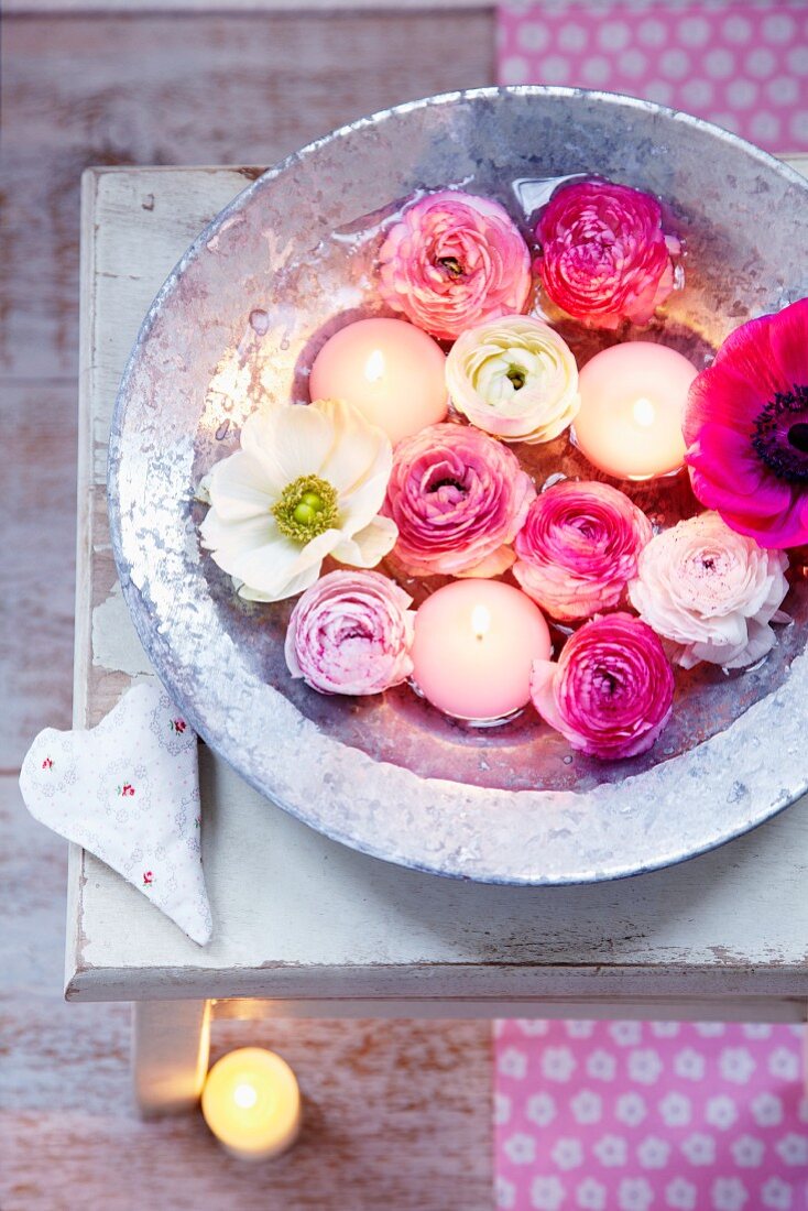 Pink and white ranunculus, anemones and floating candles in zinc bowl