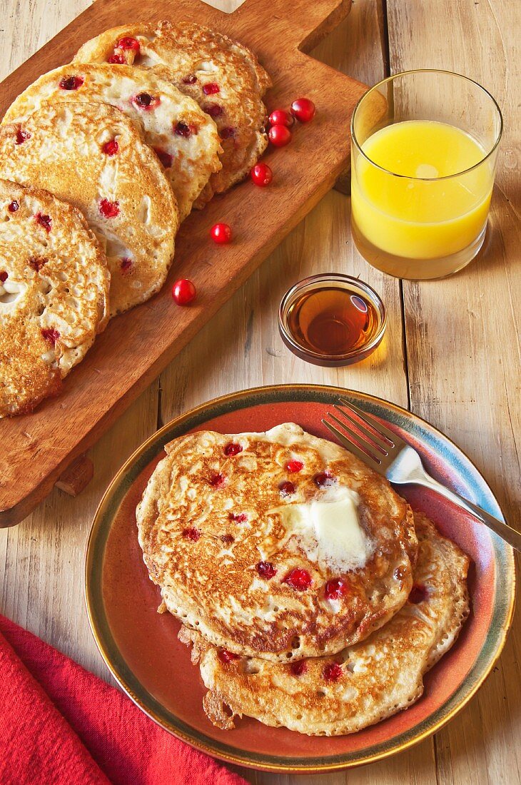 Cranberry-Pancakes mit Butter, Sirup & einem Glas Orangensaft
