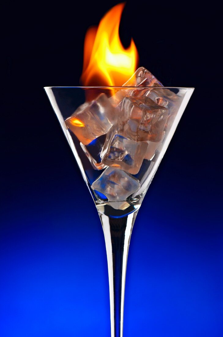 Fire and Ice; Glass of Ice Cubes with Flames; Blue Background