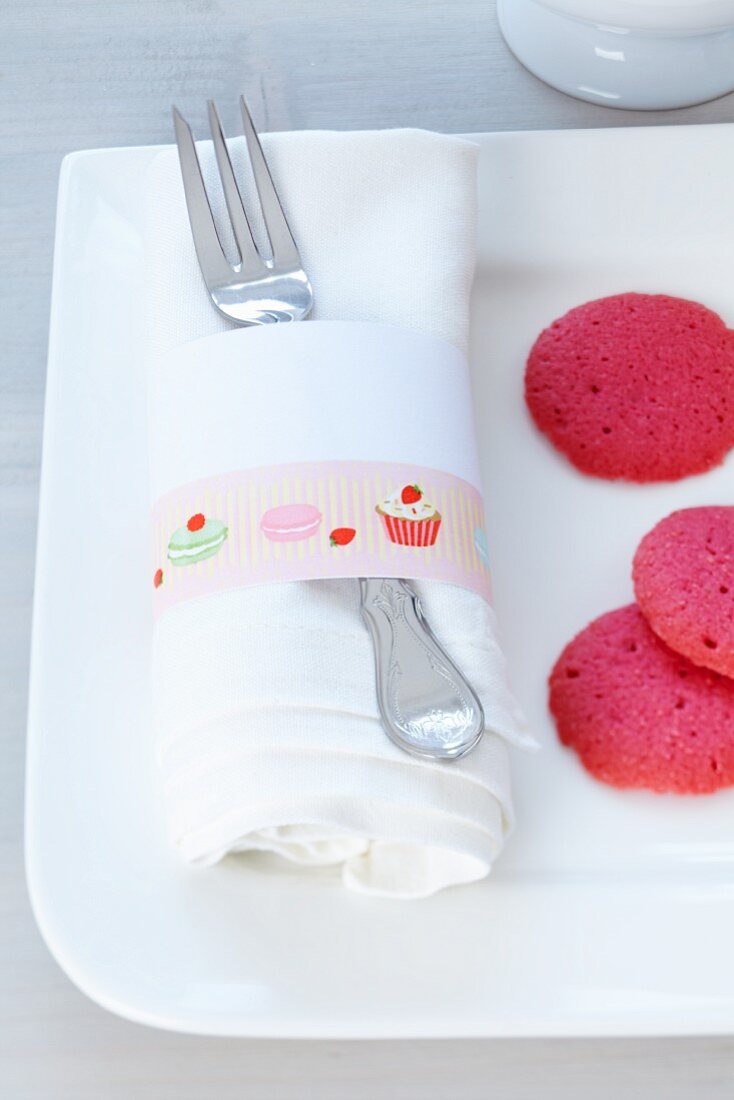 Masking Tape mit Süßigkeiten-Illlustration auf Serviettenring, Teller mit pinkfarbenen Keksen