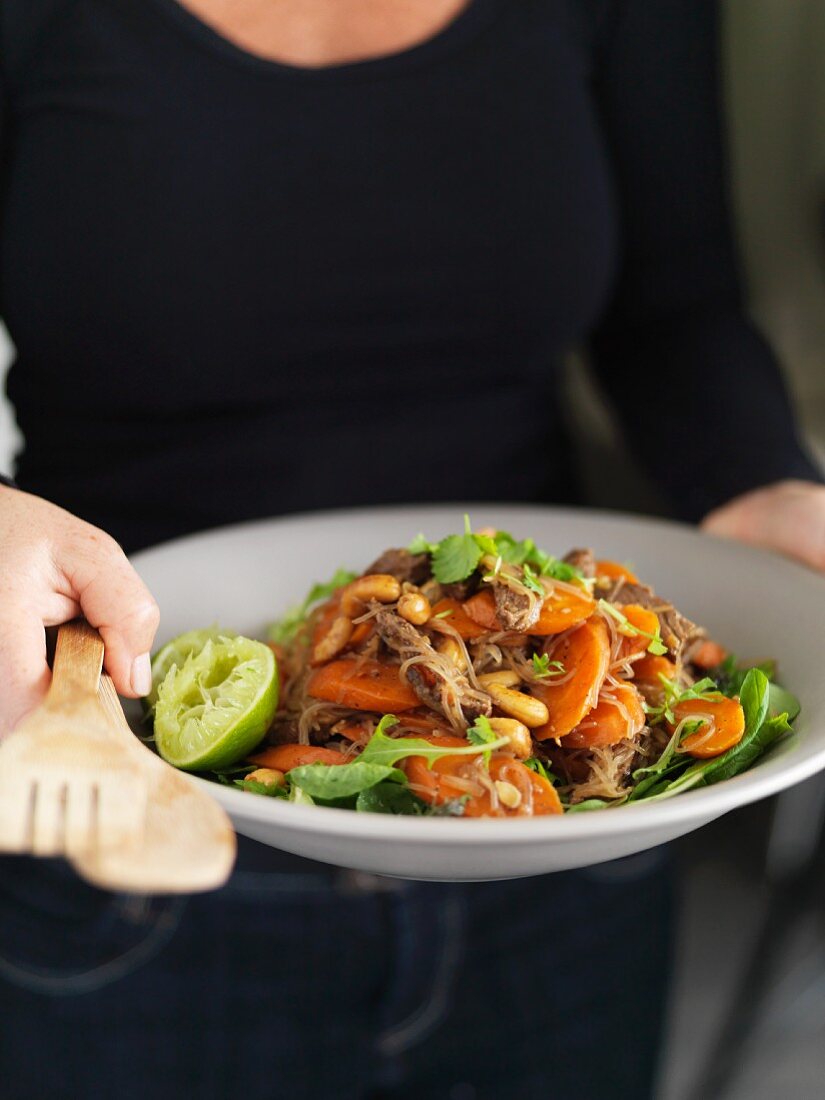 Frau serviert Rindfleisch-Chili-Salat mit Möhren