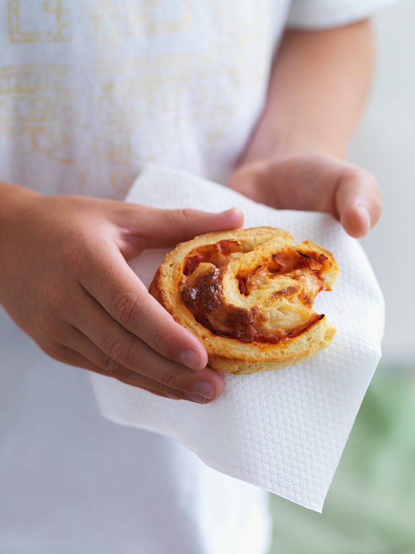A girl holding a spicy pastry on a paper napkin