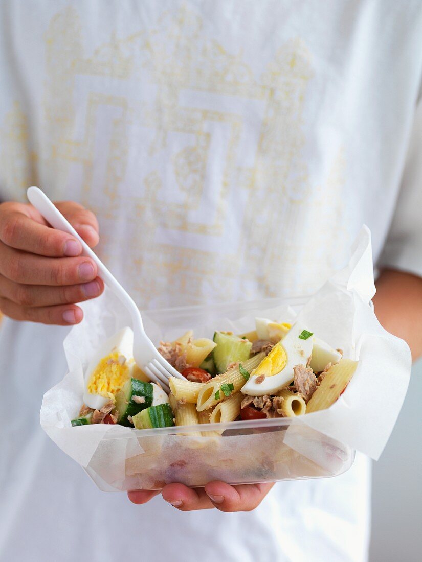 Person hält Lunchbox mit Nudel-Thunfisch-Salat