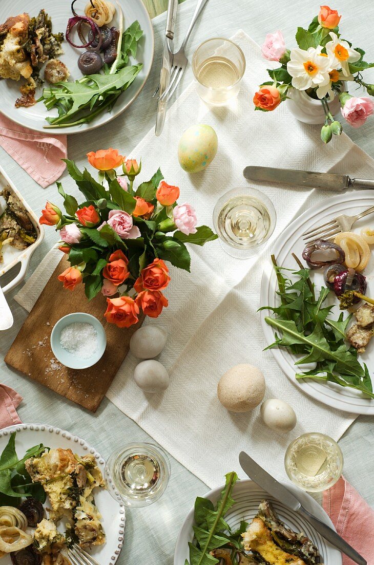 Ostertisch mit Gerichten, Blumen, Ostereiern und Wein