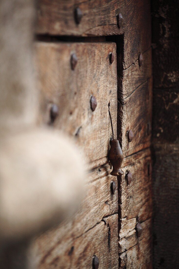 Makeshift door knocker on old wooden door with metal studs