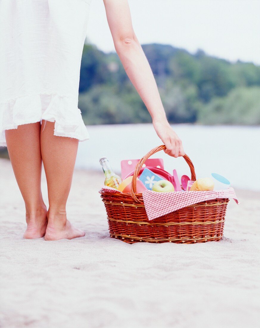 A woman with a picnic basket on a beach