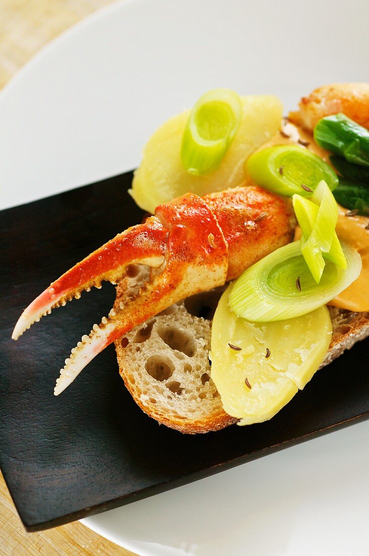 A sliced of bread topped with crab, crab mayonnaise and leek