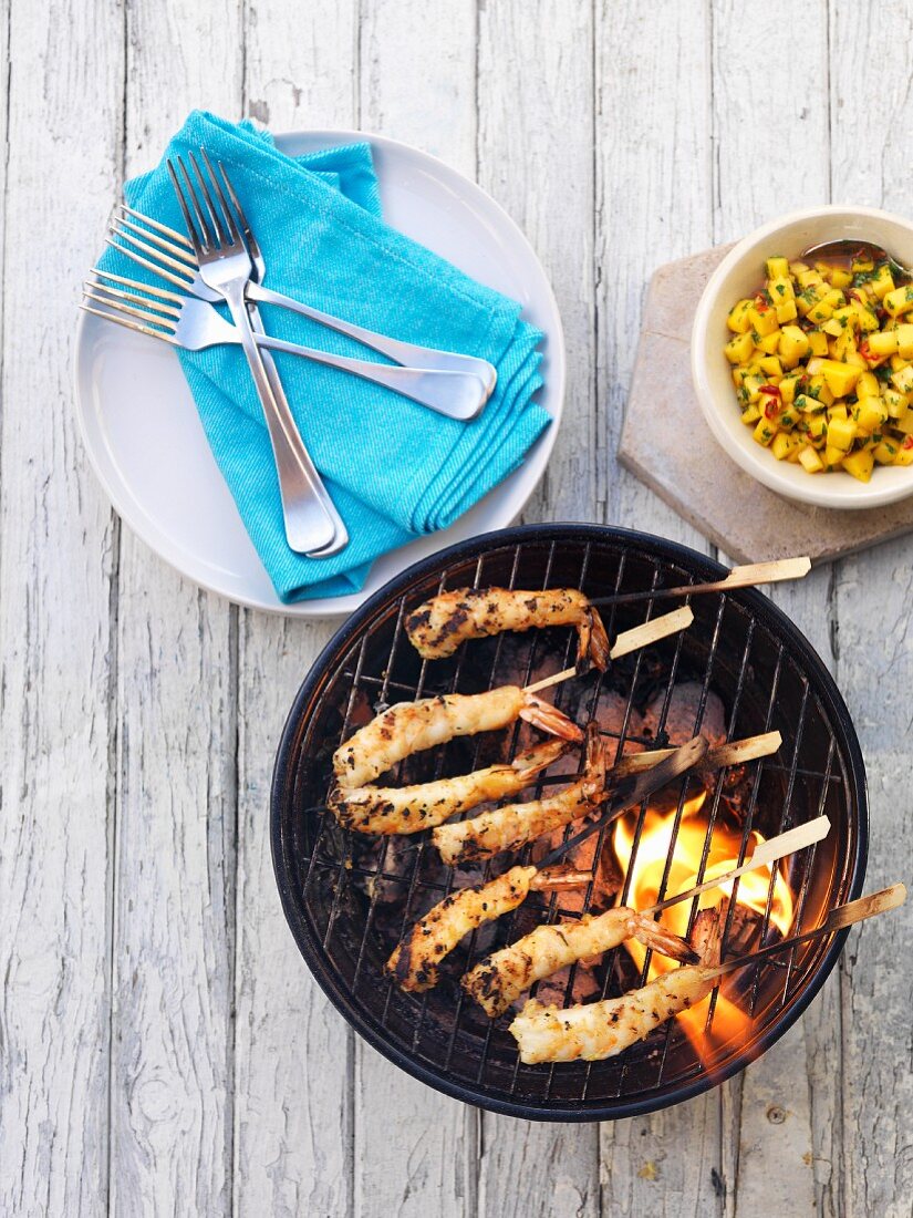 Prawn kebabs on a barbecue with mango salsa