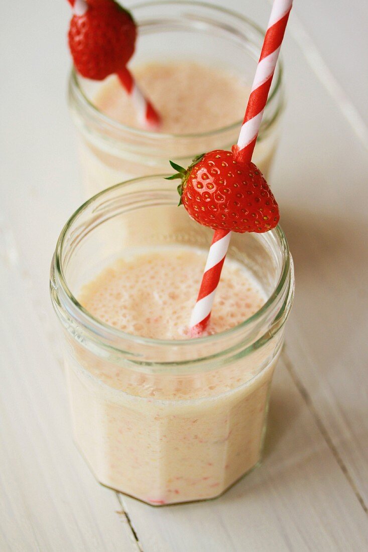 Banana milkshakes with straws and a strawberries