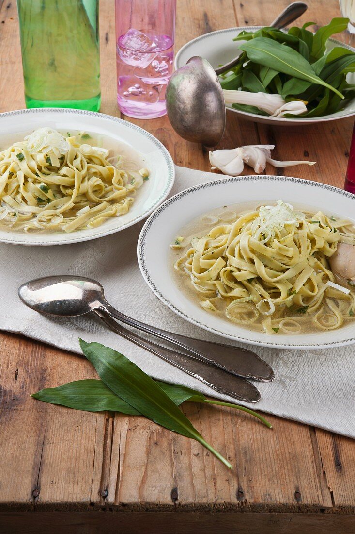 Chicken broth with ramson pasta on a wooden table
