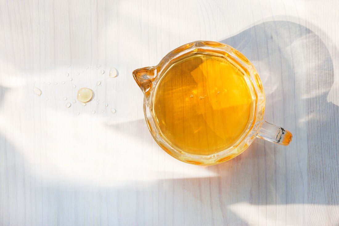 Agavensirup in einem Messbecher mit Tropfen auf Holztisch