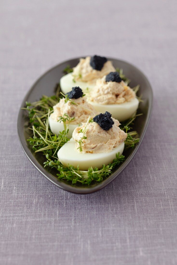 Stuffed eggs with smoked mackerel paste and caviar on a bed of cress