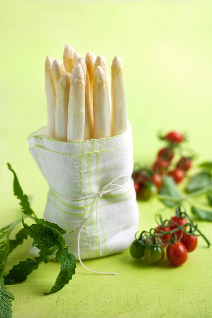 White asparagus wrapped in a tea towel and cocktail tomatoes