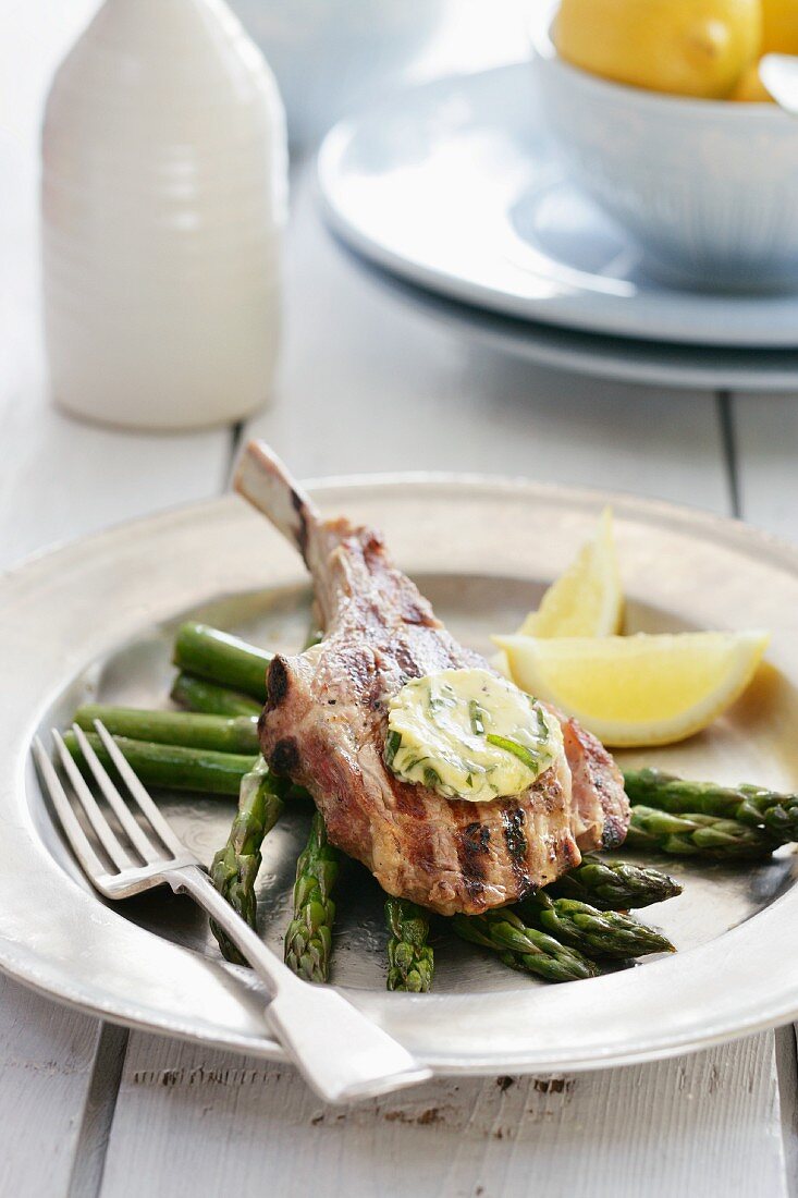 Veal chop with basil butter on a bed of green asparagus