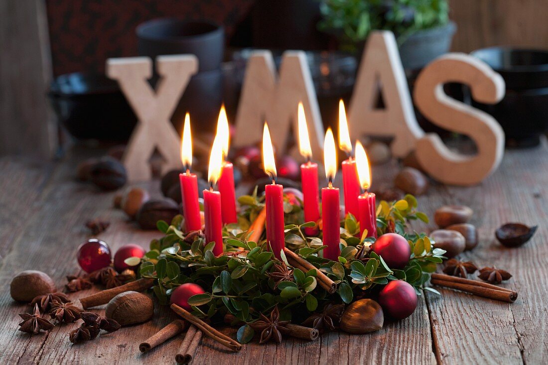 A box wreath with candles, chestnuts, cinnamon sticks and Christmas baubles