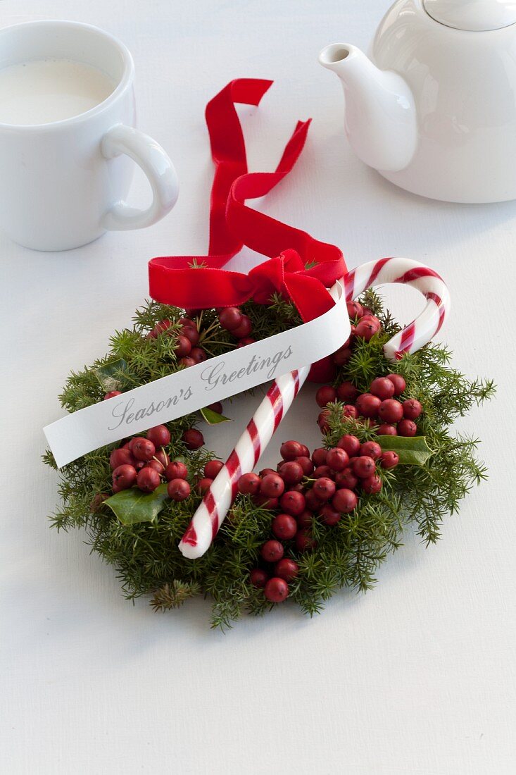 Weihnachtskranz aus Ilexbeeren und Koniferen mit Zuckerstange