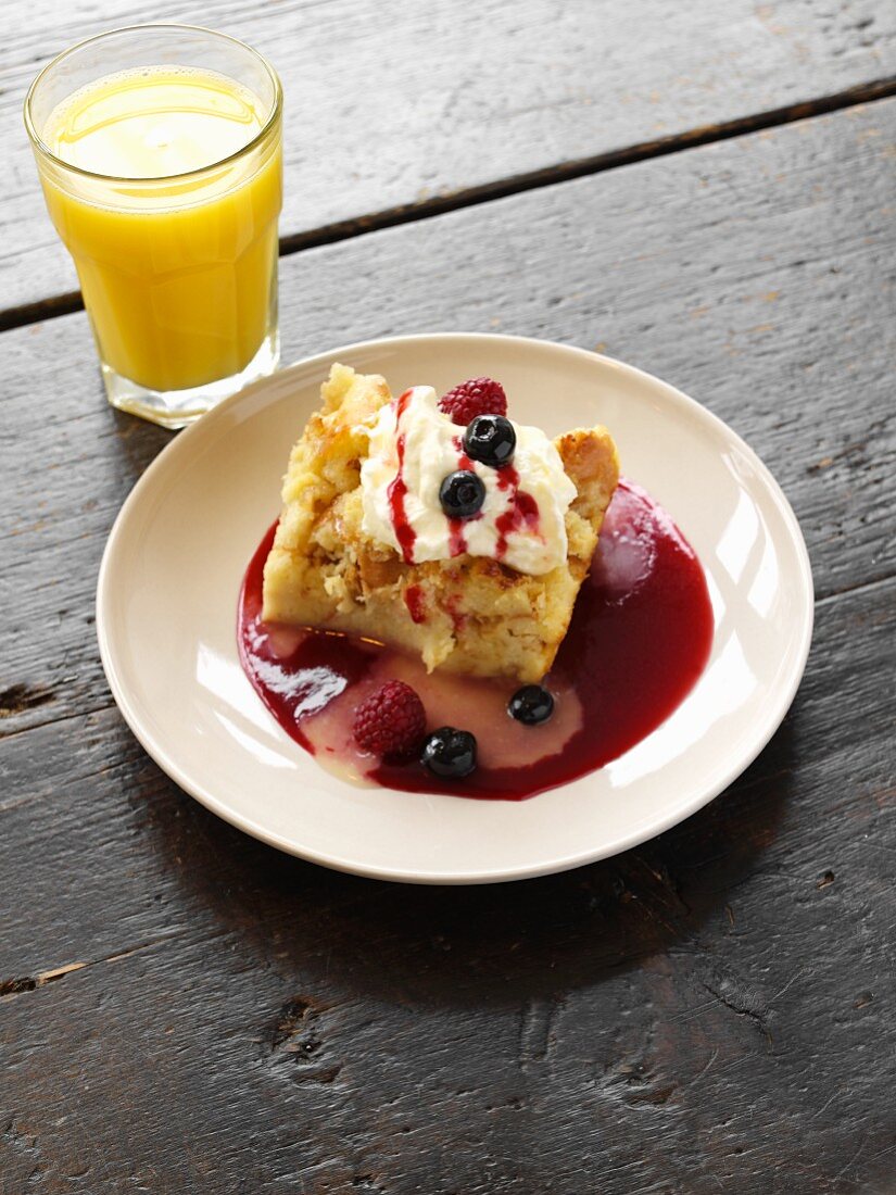 Serving of Baked French Toast with Whipped Cream and Berry Sauce; Glass of Orange Juice