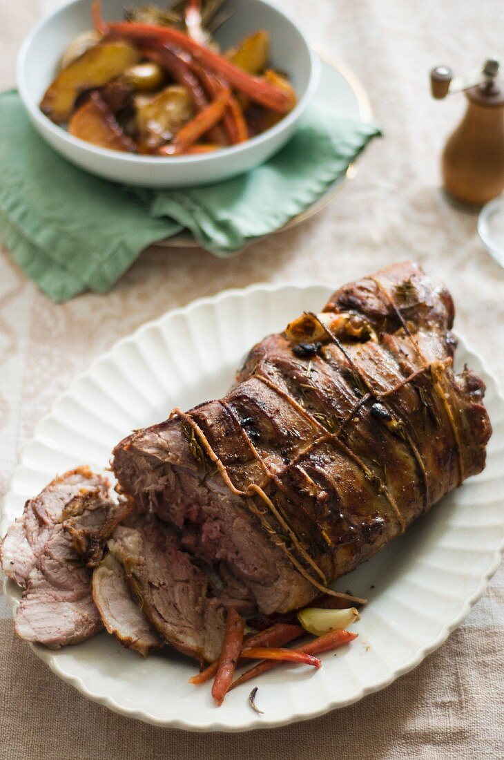 Roasted Lamb on a Serving Platter; Partially Sliced; Roasted Vegetables