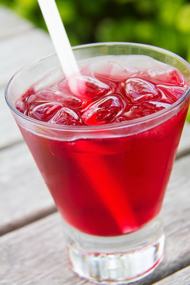 Absolute Vodka and Cranberry Juice Cocktail in a Glass with Ice and a Straw; Outdoors