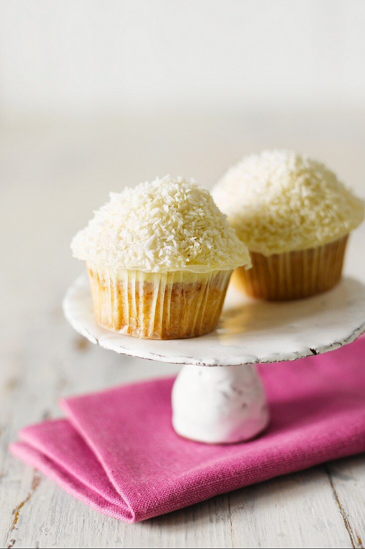Two coconut cupcakes on a cake stand