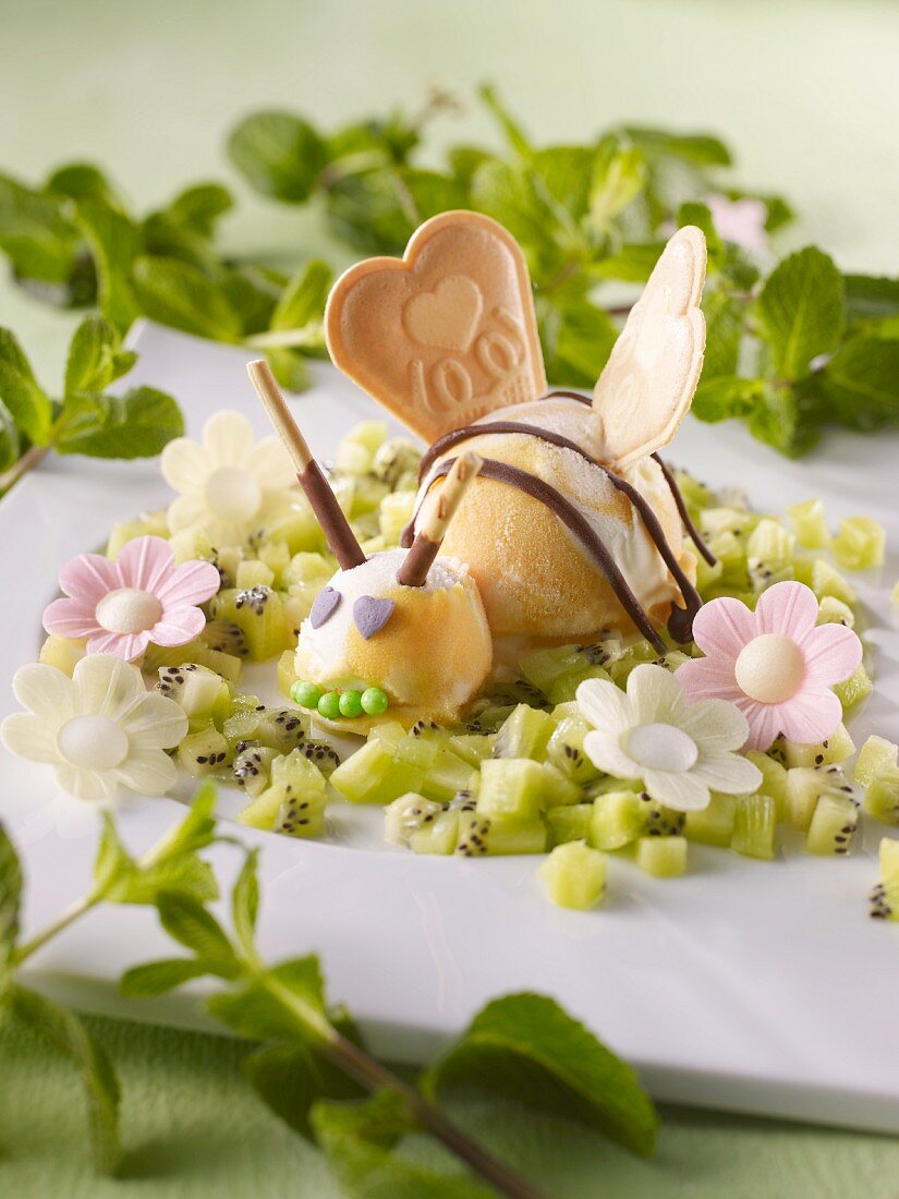 Mangosorbet in Bienenform und Esspapierblumen auf Kiwisalat