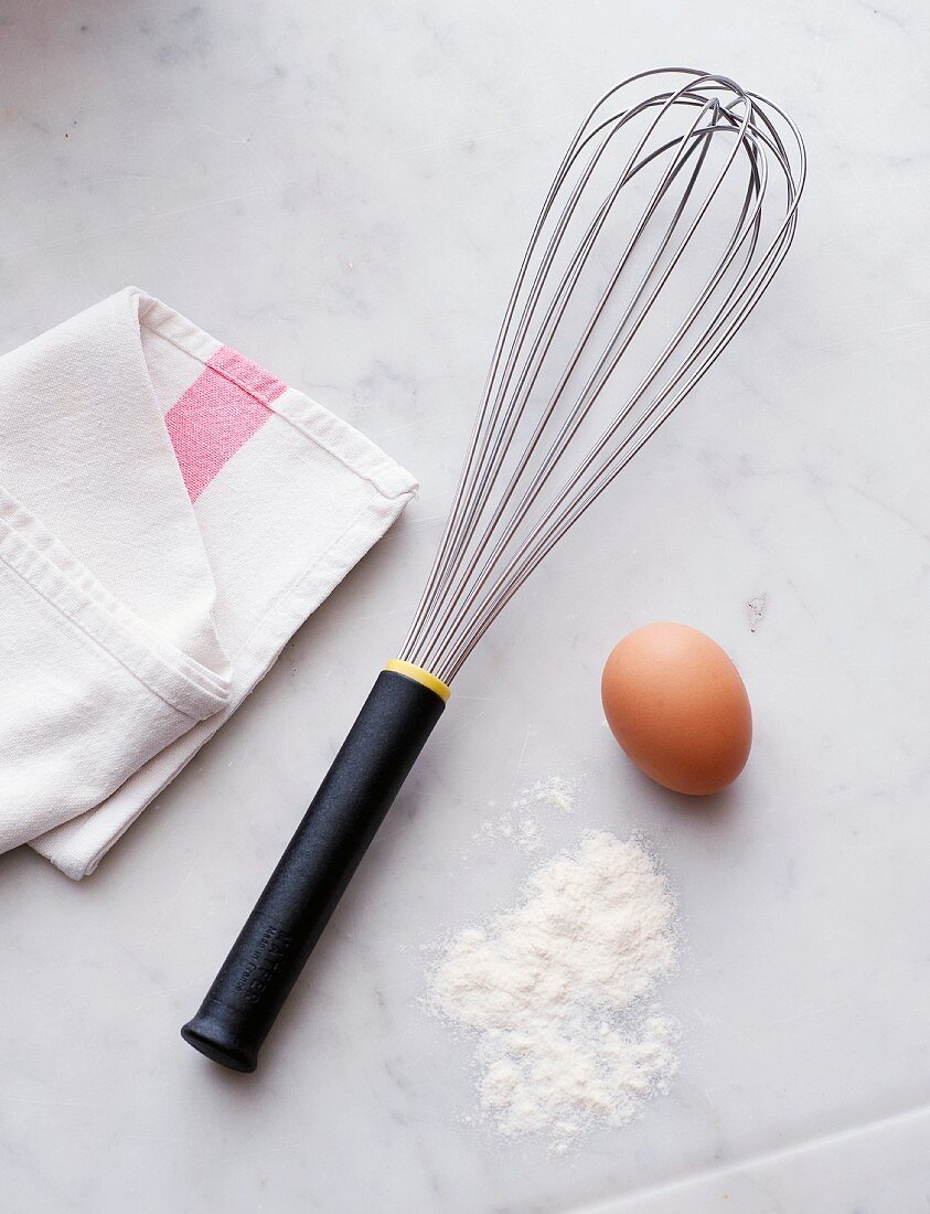 A whisk, eggs and flour