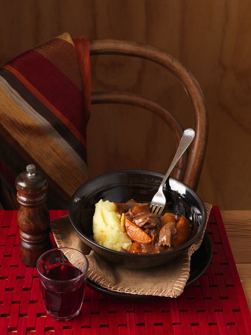 Braised lamb with mashed potatoes on a table with wine