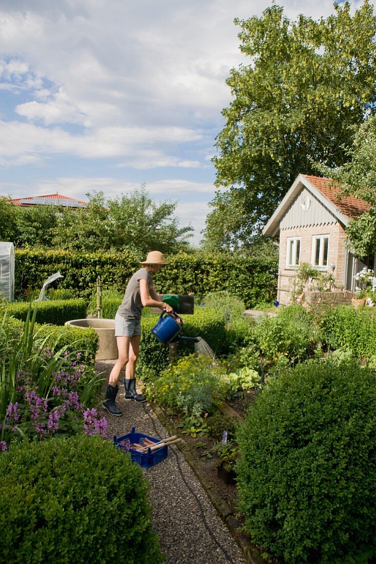 Woman watering plants in backyard