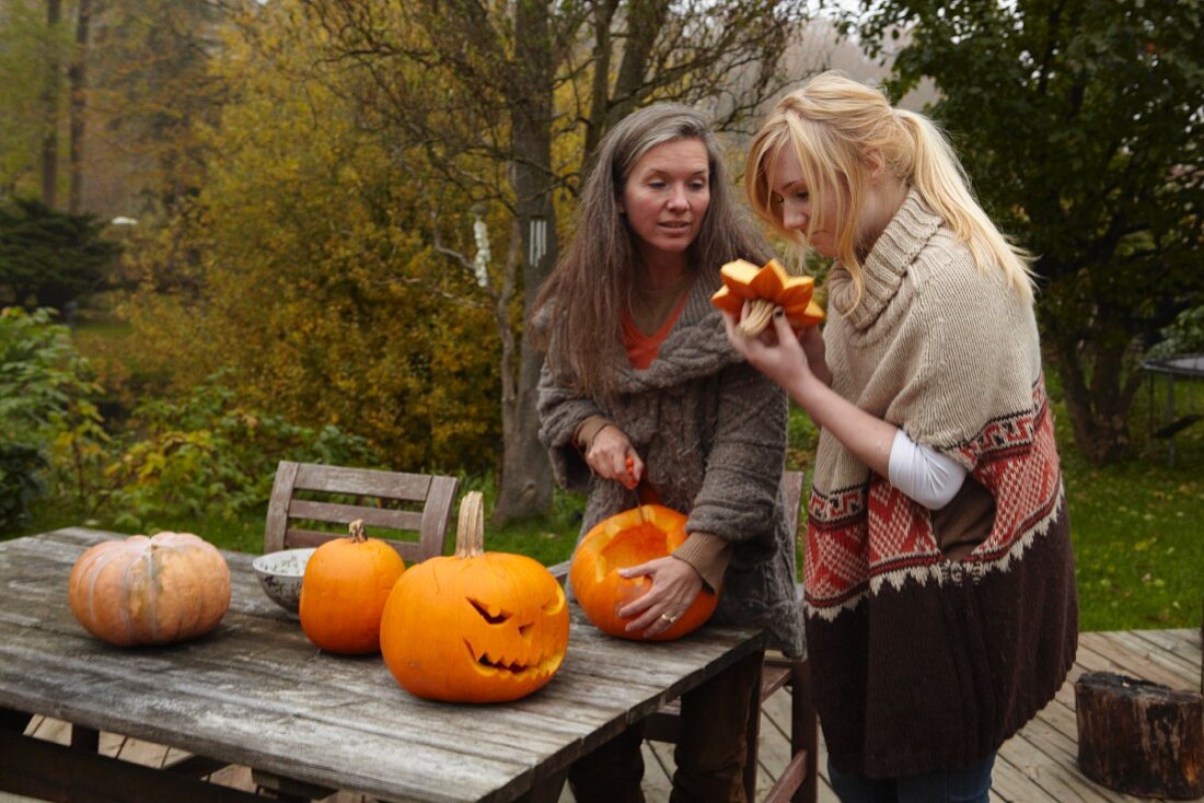 A mother and daughter cutting pumpkins in a garden