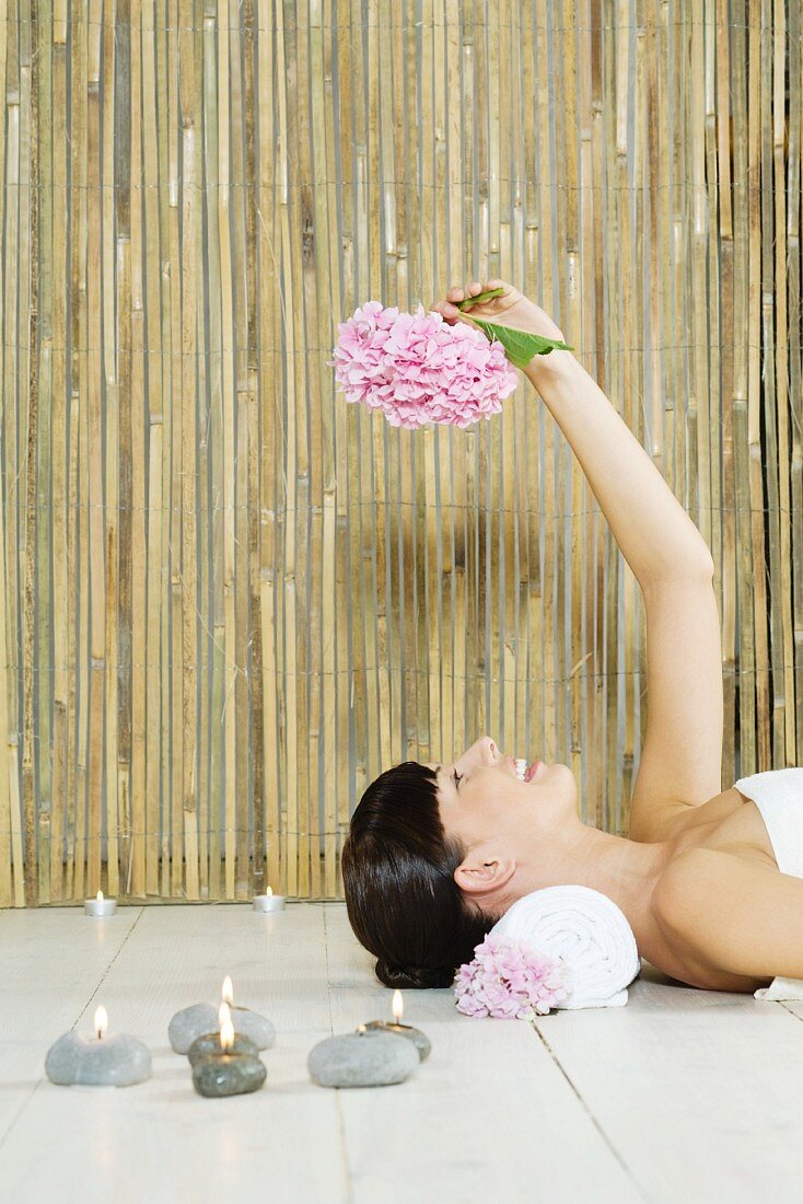 Meditationsraum - Frau auf Boden liegend hält eine Hortensie in der Hand