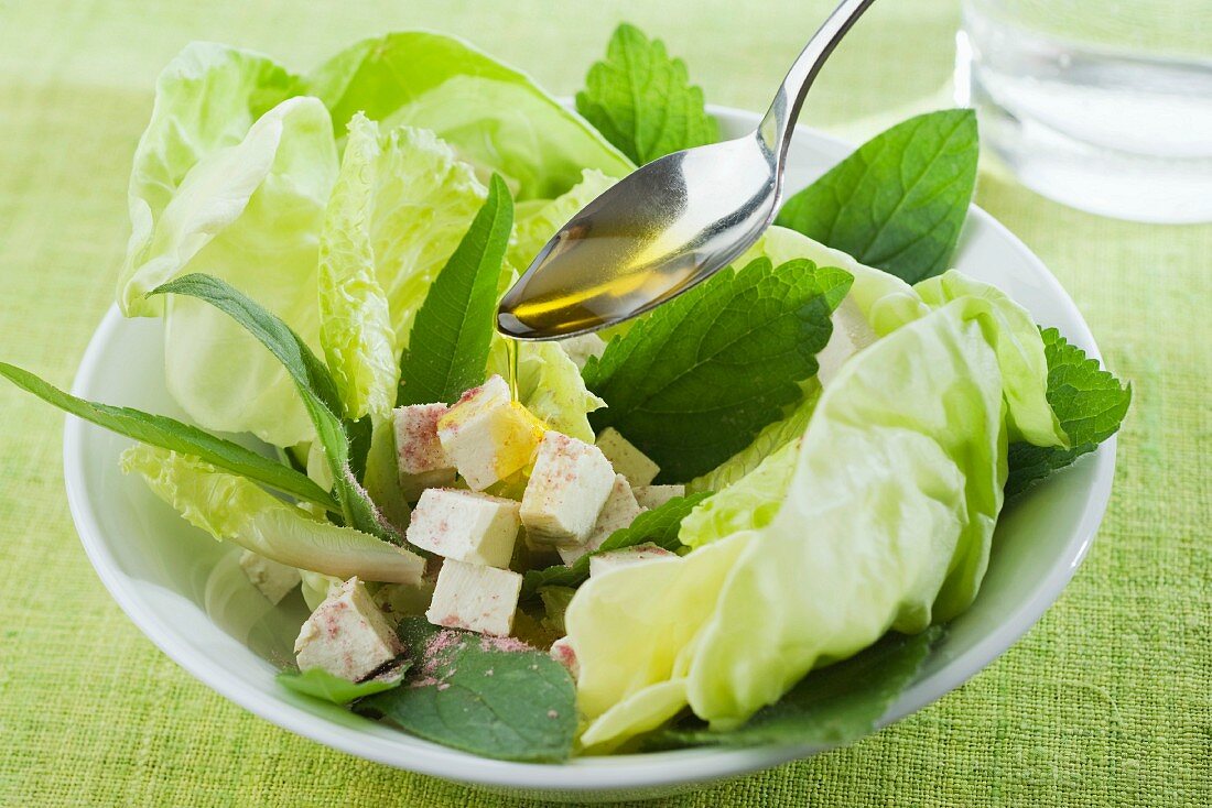 Öl auf gemischten Blattsalat mit Tofu träufeln