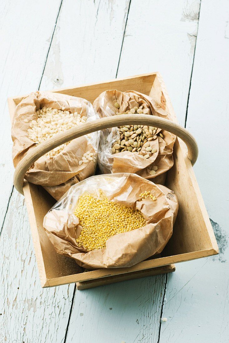 Bags of lentils, millet and short grain white rice in wooden basket