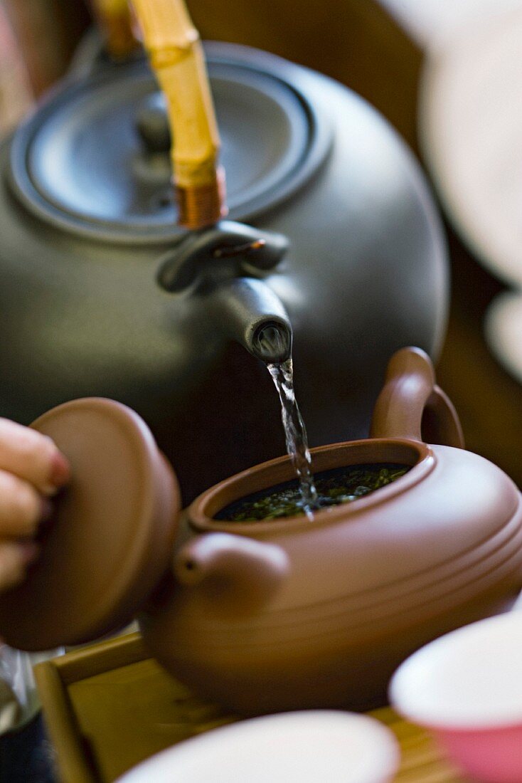 Hot water being poured from kettle into brewing teapot