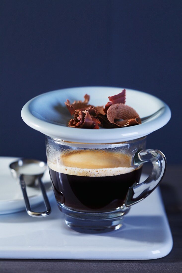 Espresso in Glastasse mit Schokoladenraspeln auf Teller