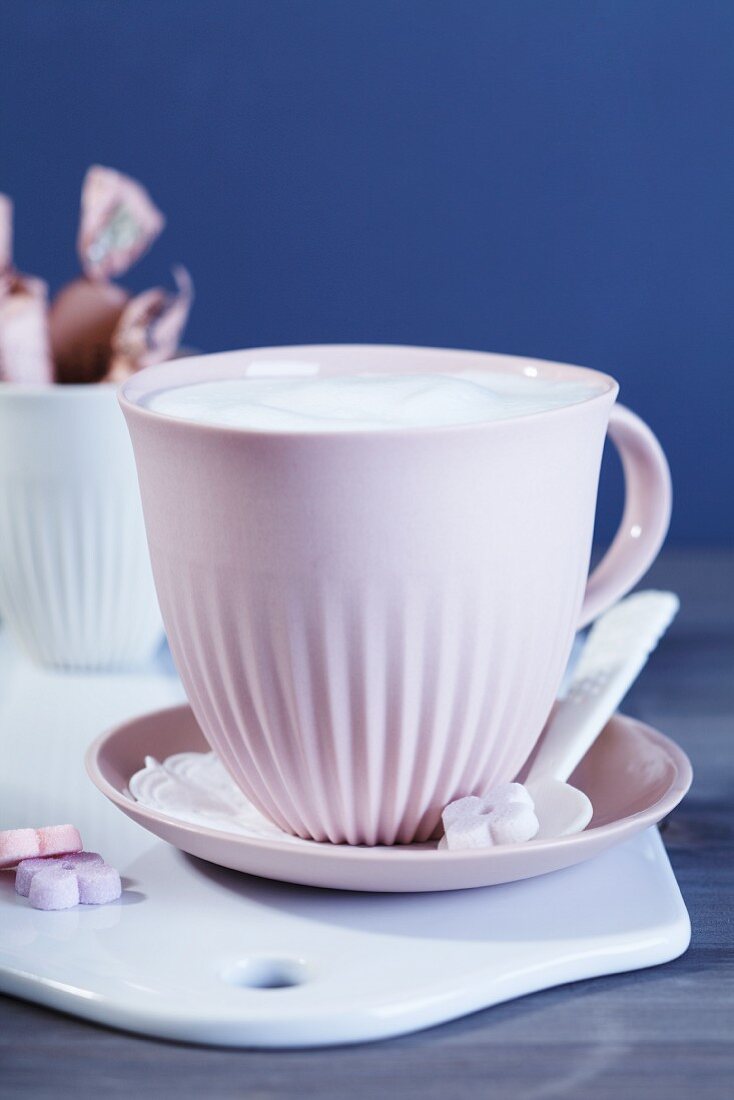 Milchkaffee oder Kakao mit Milchhaube und Zucker in Blütenform