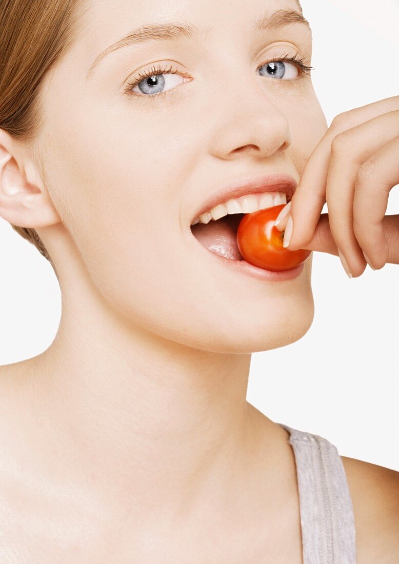 Woman biting into cherry tomato