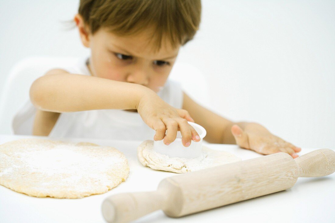 Little boy cutting out shape in dough