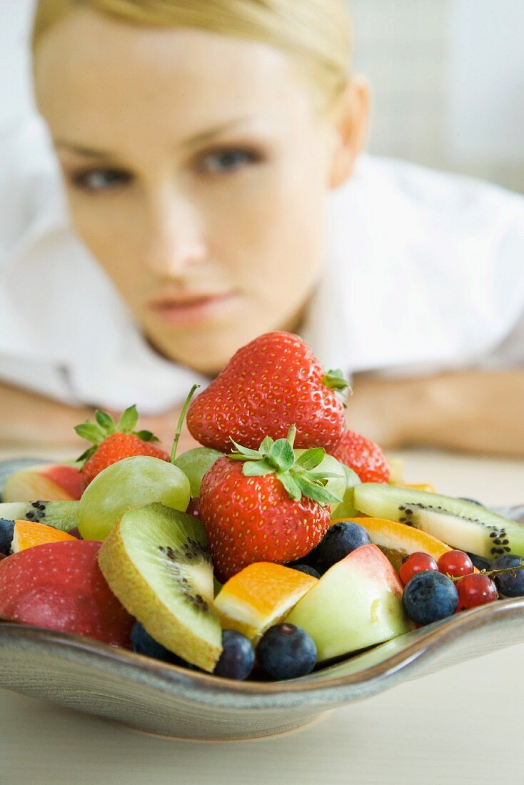 Woman looking at plate of fruit salad